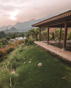 a person walking on a porch with a grass field at Sumberkima Hill 3 in Pemuteran