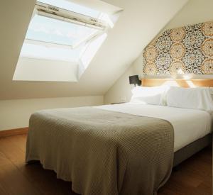 a bedroom with a large bed with a skylight at Hotel Estepona Plaza in Estepona