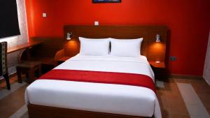 a bedroom with a large bed with a red wall at October 1st Hotel in Ibadan