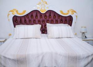 a bedroom with a white bed with a red and gold headboard at Maridel Home in Yaoundé