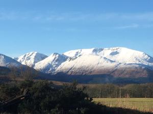 a snow covered mountain in the middle of a field at Rowantree View in Roybridge