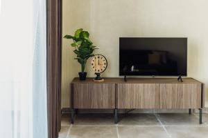 a tv on a wooden stand with a clock and a plant at St Julians`s Boho Apartments in Is-Swieqi