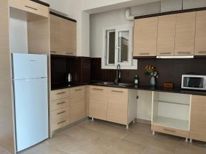 a kitchen with wooden cabinets and a white refrigerator at Thalassa View VB2 in Khalkoútsion