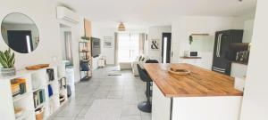 a kitchen and living room with a wooden counter top at Jolie villa avec piscine chauffée proche du lac in Sanguinet