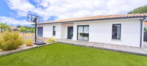 a house with a green lawn in front of it at Jolie villa avec piscine chauffée proche du lac in Sanguinet
