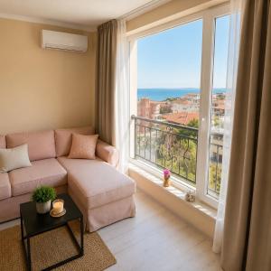 a living room with a couch and a large window at Bratanov Sveti Vlas Apartments in Sveti Vlas