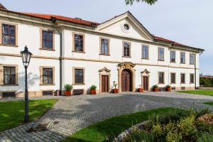 a large white house with a cobblestone driveway at Hotel Adalbert in Prague