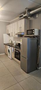 a kitchen with a stove and a washer and sink at Astros Lodge in Cape Town