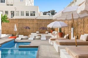 a pool with lounge chairs and umbrellas next to a building at Elsewhere in Cape Town