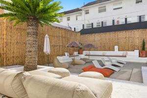a patio with couches and a palm tree and a building at Elsewhere in Cape Town