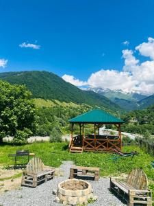 a gazebo with a table and chairs and mountains at Mountain Shadow Cottage in Racha in Ghebi