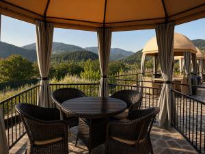 a table and chairs on a balcony with mountains at Pesvebi Design Hotel and Cellar in Borjomi
