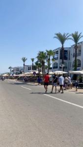 a group of people walking down a street with palm trees at Marina Puerto in Marina Smir