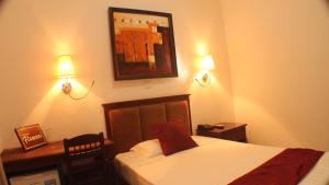 a bedroom with a bed and a desk and two lights at Hotel Residence Flamani in Lomé