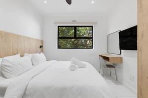 a white bedroom with a bed and a desk at Elsewhere in Cape Town