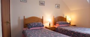 two beds in a small room with two lamps at Farmhouse in Roybridge