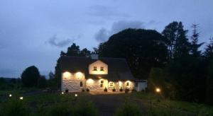 a small white house with lights on it at night at Farmhouse in Roybridge +2 photos