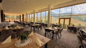 a restaurant with tables and chairs and large windows at Hotel Boboty in Terchová