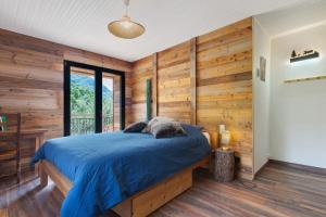 a bedroom with wooden walls and a bed with blue sheets at Gite Les Grillons in Belvédère