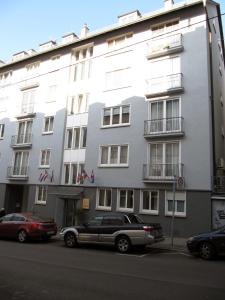 un gran edificio blanco con coches estacionados frente a él en Gästehaus Ziegler, en Stuttgart