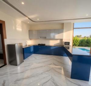a kitchen with blue cabinets and a large window at Aravali view Farmhouse in Gurgaon