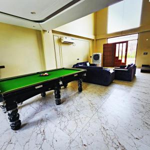 a pool table in a room with couches at Aravali view Farmhouse in Gurgaon