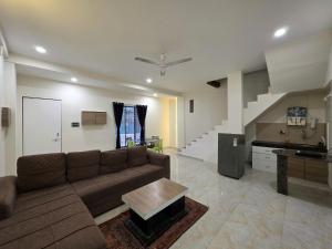 a living room with a couch and a staircase at II EMPYREAN STAYS II WHITE PANTHER VILLA II 3BHK II AC II PRIVATE POOL ll in Lonavala