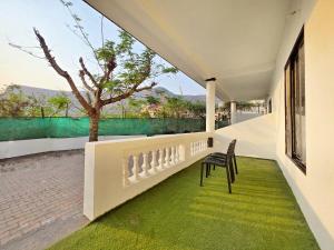 a balcony with a table and chairs and a green rug at II EMPYREAN STAYS II WHITE PANTHER VILLA II 3BHK II AC II PRIVATE POOL ll in Lonavala