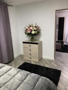 a bedroom with a dresser with a vase of flowers on it at Apartamente Gildo 20 in Borşa +2 photos