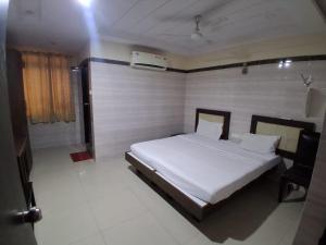a bedroom with a bed and a chair in it at Hotel 9 square in Shamshabad