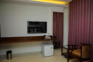 a hotel room with a tv on the wall and a chair at Hotel 9 square in Shamshabad