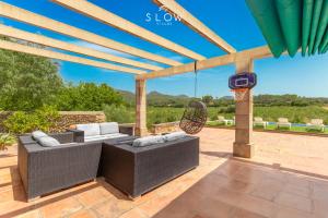 a patio with wicker furniture and a basketball hoop at Villa Son Bennasar by Slow Villas in Felanitx