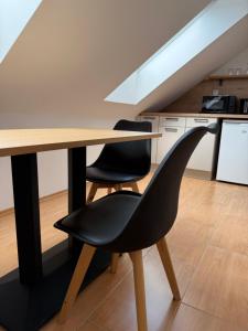 a dining room table with two black chairs next to a kitchen at Penzión Daniel in Ilava