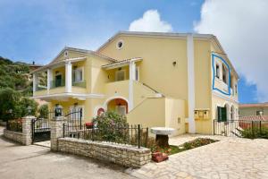 a yellow house with a fence in front of it at Dimitris Residence 2 Kalami bay in Kalami