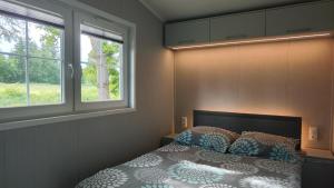 a bedroom with a bed with two pillows and two windows at Guliwer in Niechorze