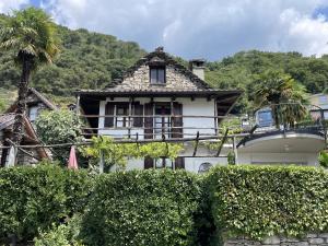 a white house with a balcony and a palm tree at Al Torchio by Fewotessin in Riazzino