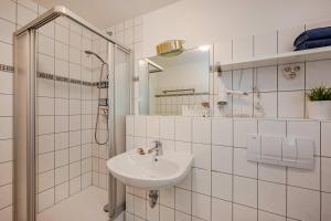 a white bathroom with a sink and a shower at Waldsiedlung Waldhaus App 4.1 in Korswandt +16 photos