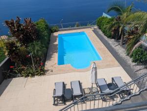 an image of a swimming pool with chairs and the ocean at Loreto Luxury in Arco da Calheta