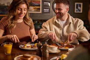a man and woman sitting at a table eating food at Offshore - The Inn Collection Group in Lytham St Annes