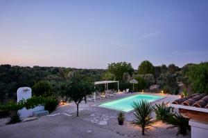 a swimming pool in a yard with chairs and trees at Trullo KAVA - Ceglie Messapica in Ceglie Messapica