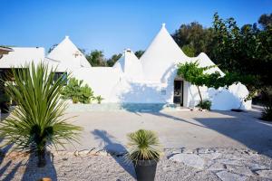 a white house with some plants in front of it at Trullo KAVA - Ceglie Messapica in Ceglie Messapica