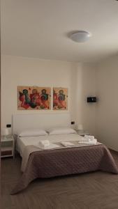 a bedroom with a bed with two paintings on the wall at B&B Dimora Elmara in San Salvo +1 photo