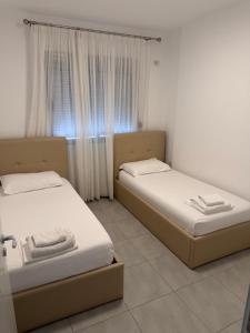 two beds sitting in a room with a window at Miramare Aparthotel in Sarandë