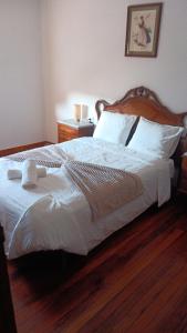 a bedroom with a large white bed with a wooden headboard at Casa dos avós in Redondela