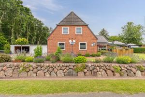 a brick house with a stone wall in front of it at Jule Ahoi in Stedesand