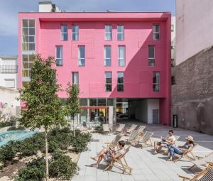 a group of people sitting in chairs in front of a pink building at Password to Madrid Casa de Campo in Madrid