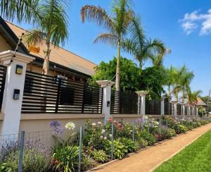 a house with a fence and flowers and palm trees at Paradise Creek Hotel in Tamale
