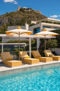 a pool with chairs and umbrellas next to a building at St George Lycabettus Lifestyle Hotel in Athens