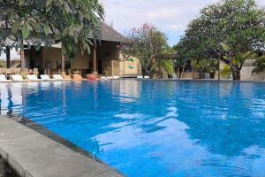 a large blue swimming pool with chairs and trees at Maruti Beach Villas in Nusa Penida +29 photos