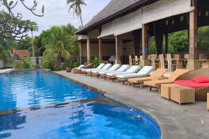a swimming pool with lounge chairs and a resort at Maruti Beach Villas in Nusa Penida